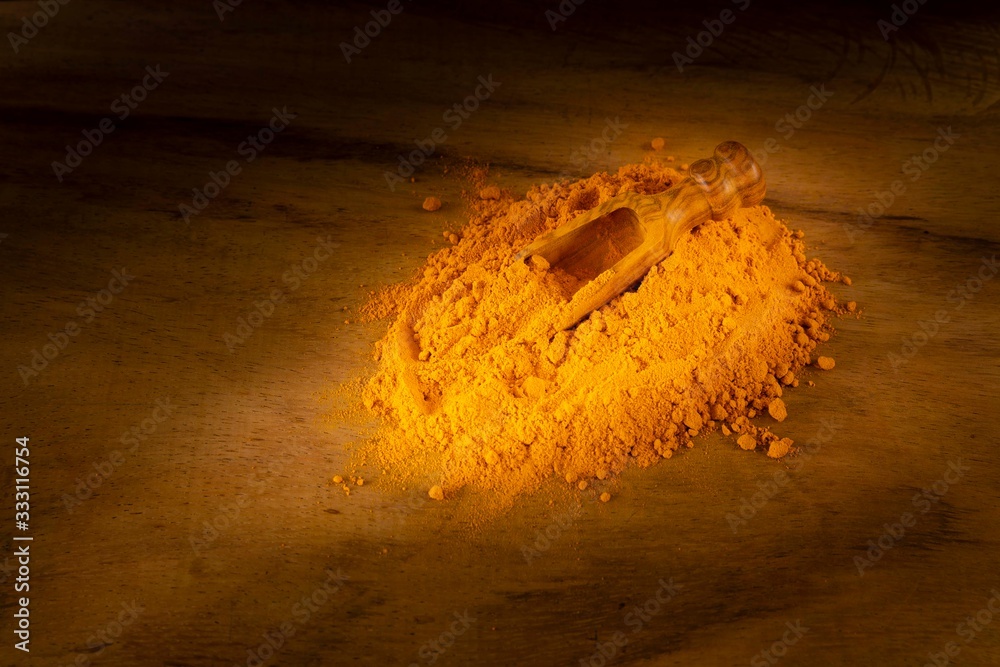 Turmeric powder and roots on a dark wooden surface Turmeric powder and roots on a dark wooden surface