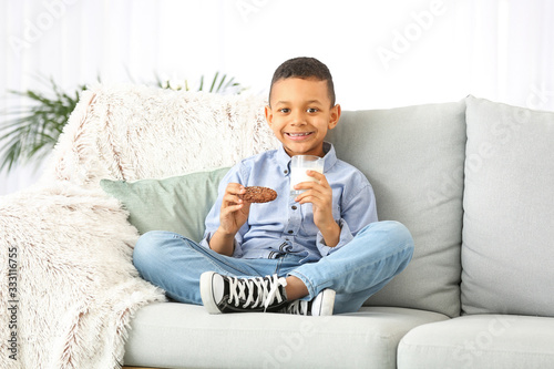 African-American boy drinking milk and eating cookie at home