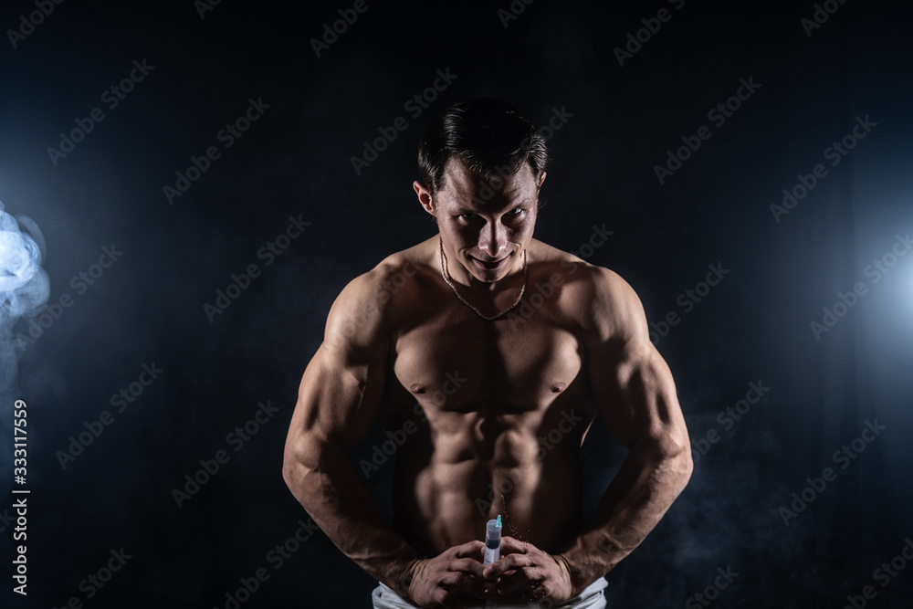 Bodybuilder holding big syringe with injection. concept of steroid in the sport and addiction 