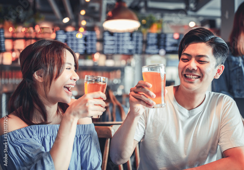 Canvas Print happy young woman with friend dining and drinking beer at restaurant