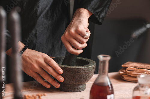 Male alchemist making elixir in laboratory, closeup photo