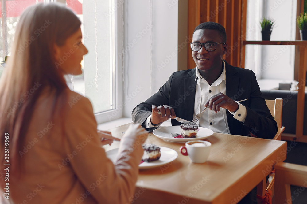 Fototapeta premium Black man in a cafe. International people. Man in a black suit. Woman in a pink jacket.