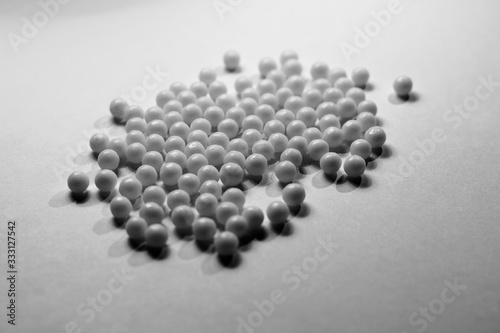 A pile of white round tablets on a white surface