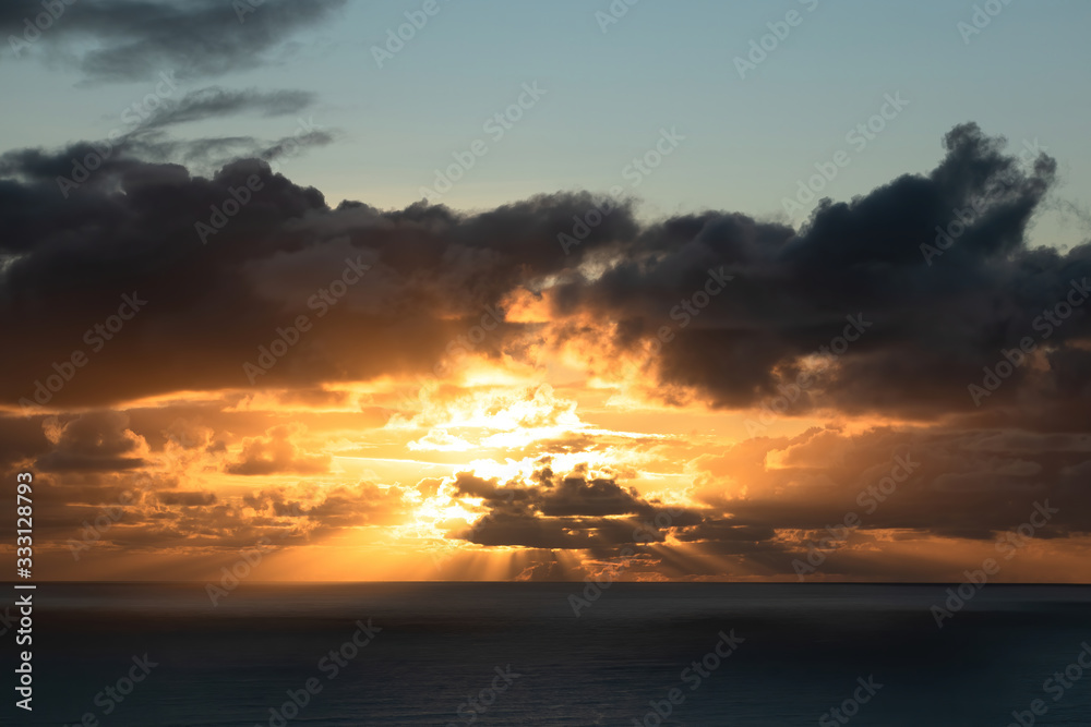 View of dark clouds lit by bright sunset light with fading blue sky above