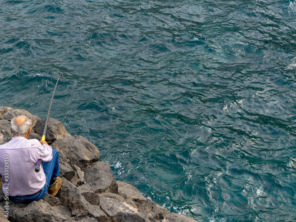 Older man fishing. Fishing is a very important activity on the island of El Hierro. Older man fishing. Fishing is a very important activity on the island of El Hierro.
