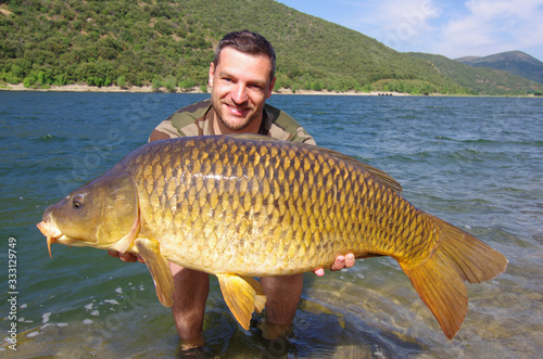 lucky fisherman holding a giant common carp. Freshwater fishing