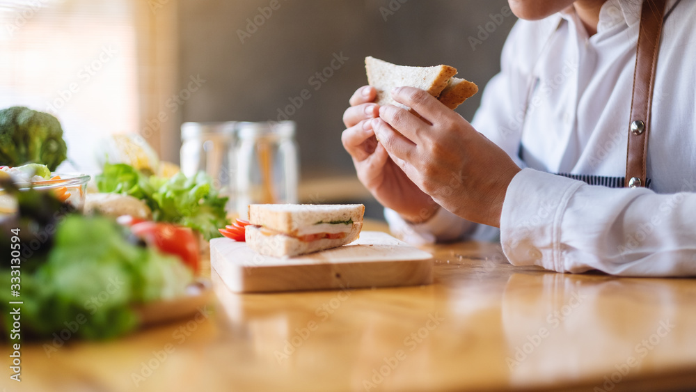 Closeup image of a female chef cooking and eating a whole wheat sandwich in kitchen Closeup image of a female chef cooking and eating a whole wheat sandwich in kitchen