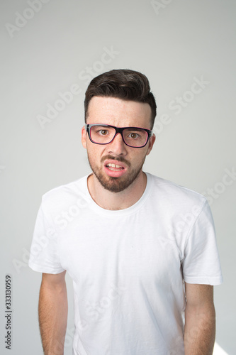 Young man isolated over background. Vertical picture of nerd or weirdo look straight through glasses. Boring and unhappy guy. Stand alon in white shirt. © estradaanton