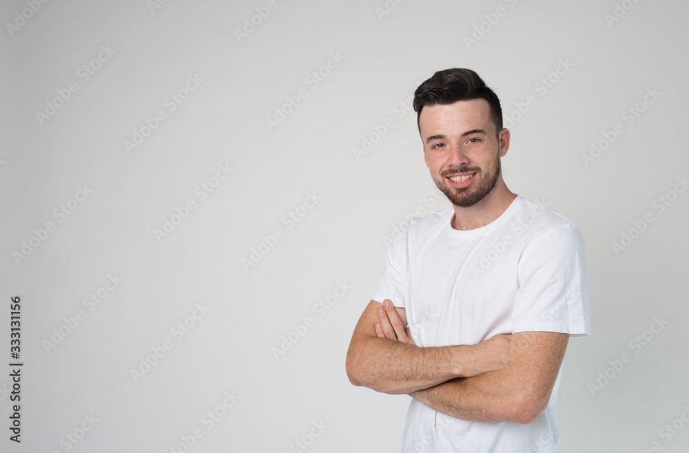 Young man isolated over background. Confident attractive guy hold hands crossed and pose on camera. Alone in studio. Cheerful positive guy on picture.
