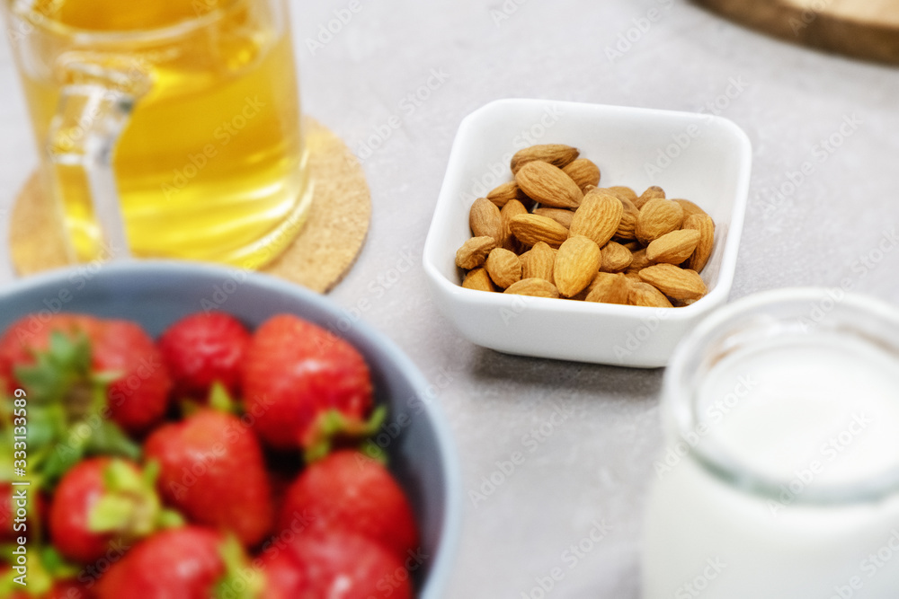Almond in a bowl on the table next to fresh milk, strawberries and warm herbal tea. Morning in the village. Ingredients for a healthy smoothie. Almond in a bowl on the table next to fresh milk, strawberries and warm herbal tea. Morning in the village. Ingredients for a healthy smoothie.