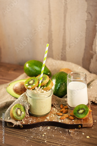 Fresh smoothie made of kiwi, avocado, oatmeal and skim milk near a burlap towel. Decorated on top. Morning meal in the village with fresh ingredients.