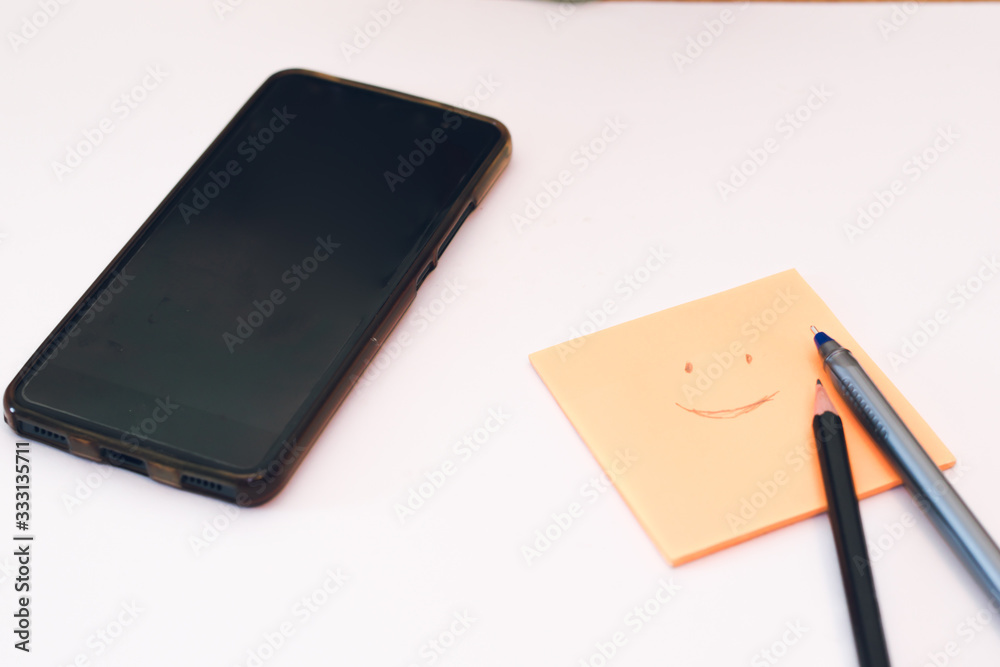 Creative flat lay photo of workspace desk with paper sticker, smartphone, pen and pencil. Work from home during Coronavirus pandemic quarantine isolation. Working remotely home concept Creative flat lay photo of workspace desk with paper sticker, smartphone, pen and pencil. Work from home during Coronavirus pandemic quarantine isolation. Working remotely home concept