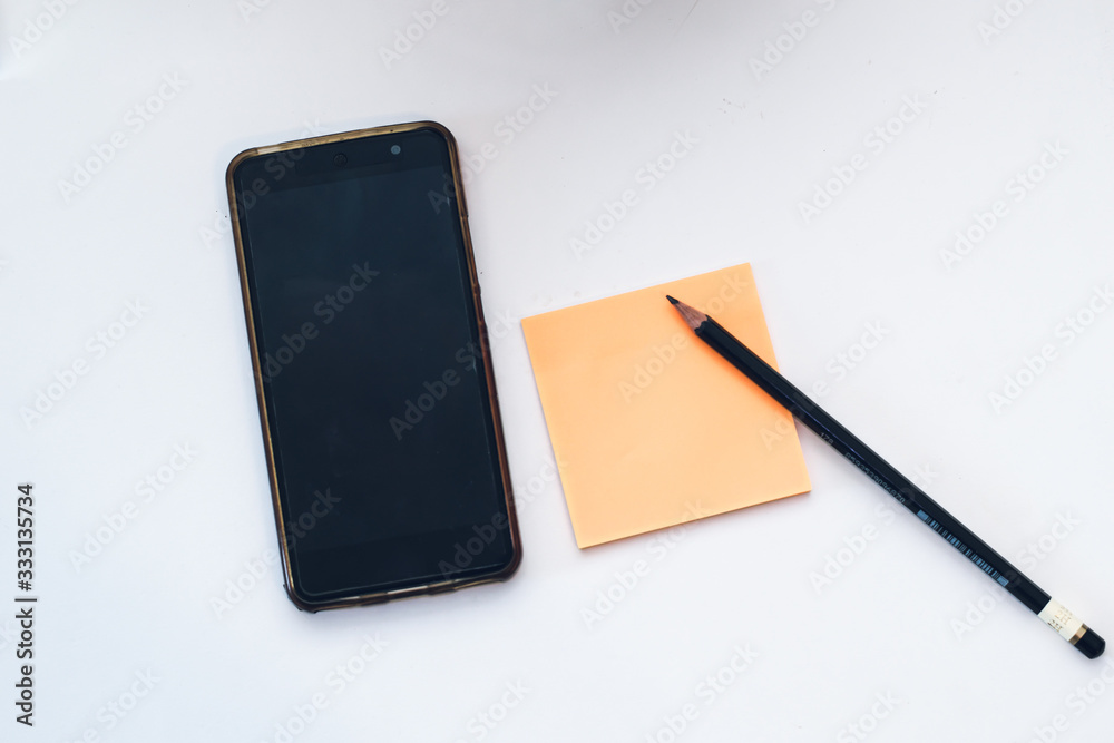 Creative flat lay photo of workspace desk with paper sticker, smartphone, pen and pencil. Work from home during Coronavirus pandemic quarantine isolation. Working remotely home concept Creative flat lay photo of workspace desk with paper sticker, smartphone, pen and pencil. Work from home during Coronavirus pandemic quarantine isolation. Working remotely home concept