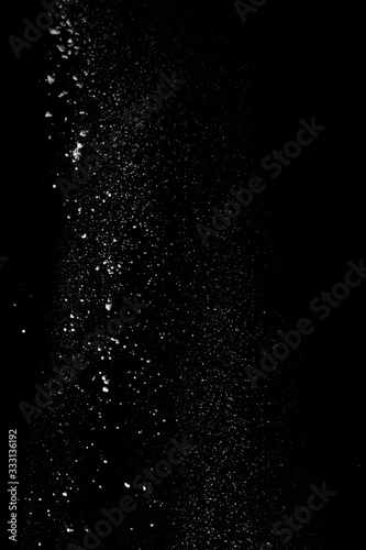 White dust similar to flour and snow is actively scattered isolated on black background