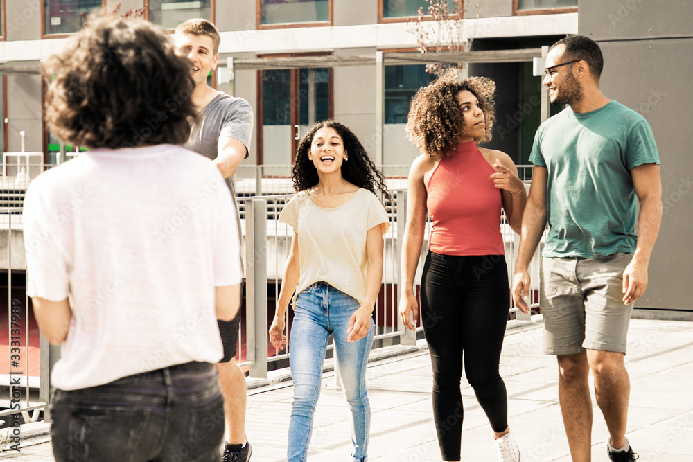 Obraz premium Happy friends walking outdoors. Cheerful young multiethnic men and women walking and talking together on street. Communication concept