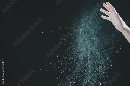 Hand of european woman chef in kitchen pouring flour on black background