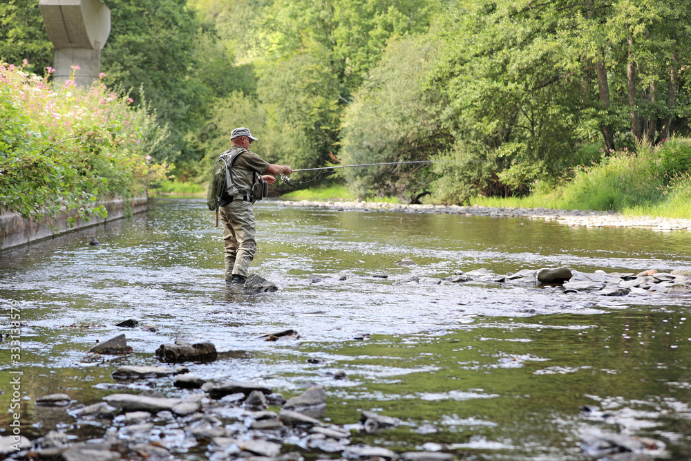 trout fisherman in action on a small river trout fisherman in action on a small river