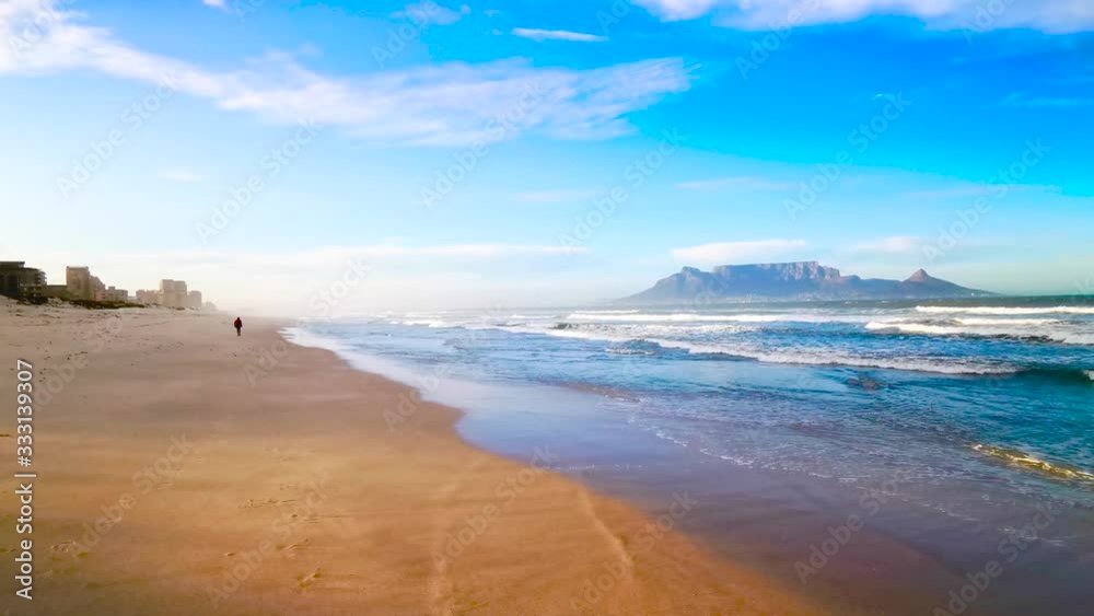 One person walking along the scenic beach next to the ocean. One person walking along the scenic beach next to the ocean.