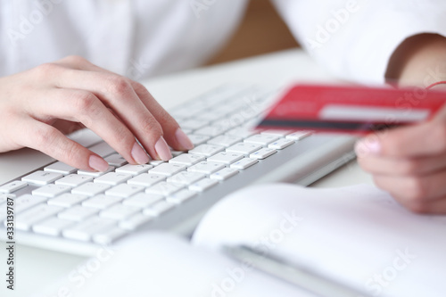 Female hands hold credit card  pressing buttons and making online purchase closeup. Anti-fraud and financial security  entering client discount program number  filling personal information concept