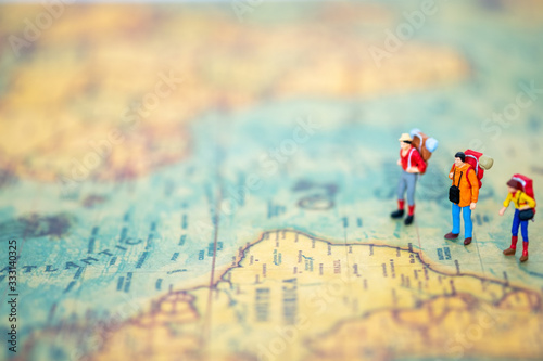 Miniature people: Group of backpacker on vintage world map using as business trip traveler adviser agency or explorer on earth background concept.
