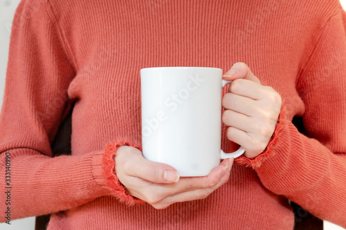 Mug mockup. Women's hands holding mug with blank space for your text or promotional content.