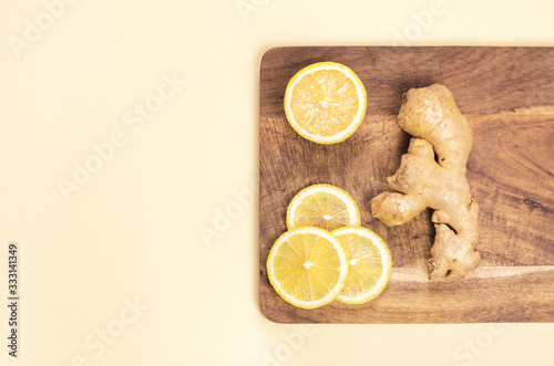 Lemon and ginger root on a wooden board and a yellow background.