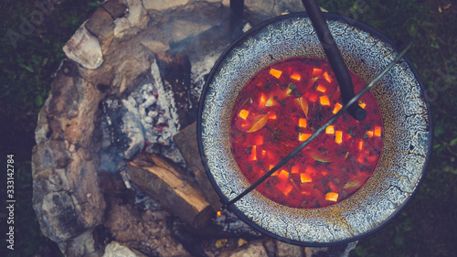 Cooking goulash soup in a cauldron on open fire in the woods