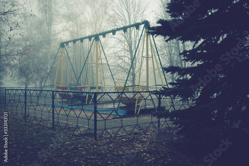 Swing boats in an old abandoned park on a foggy autumn morning