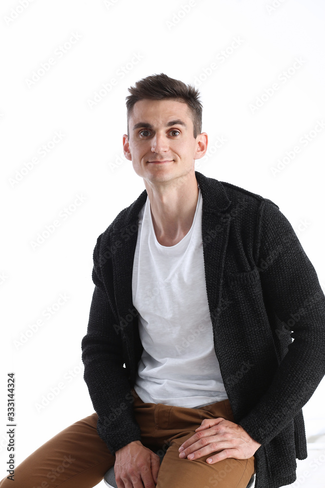 Portrait of an attractive man in a sweater and a T-shirt, sitting on a chair and smiling Portrait of an attractive man in a sweater and a T-shirt, sitting on a chair and smiling