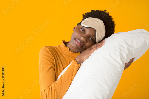 Fototapeta Naklejka Na Ścianę i Meble -  beautiful young african woman on a yellow background with a pillow