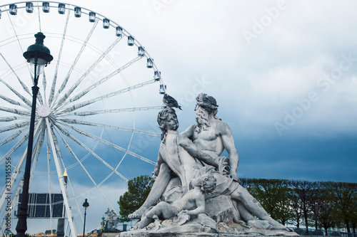 Paris touristic square with garden, sculpture and big ferris wheel on cloudy sky photo