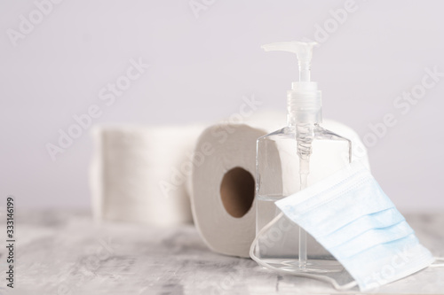 Background for the disinfection of coronavirus. Sanitizer, protective medical mask, rolls of toilet paper. Compliance with disinfection, cleanliness, hand wet