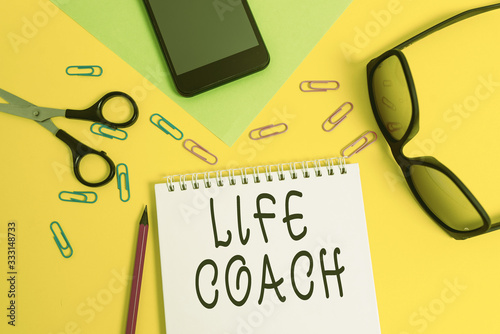 Writing note showing Life Coach. Business concept for someone who helps identify your goals and plan to achieve them Sheet pencil smartphone scissors eyeglasses notepad color background photo