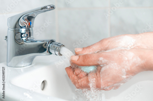 Woman soap her hand under a faucet with running water