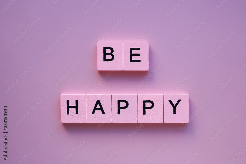 Be happy word wooden cubes on a pink background Be happy word wooden cubes on a pink background