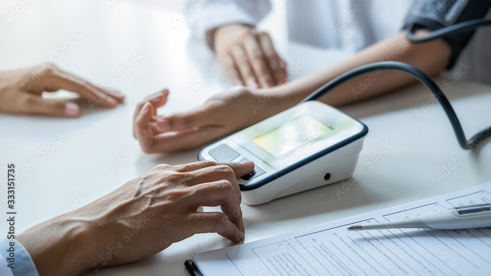 Fototapeta premium Doctor measuring patient blood pressure in clinic or hospital office. Medical and Health concept.