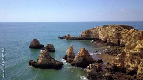 Aerial, rising, drone shot over rocks and cliff, at the Ponta joao de arens viewpoint, near Alemao Beach, sunny day, in Portimao, Algarve, Portugal photo
