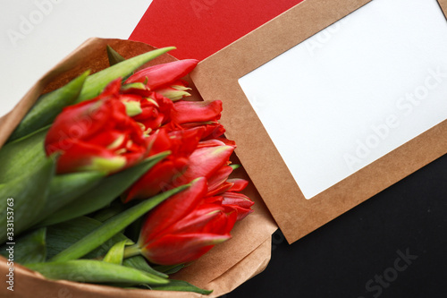 bunch of red tulips in craft paper with a frame with blank space for copy text, top view photo