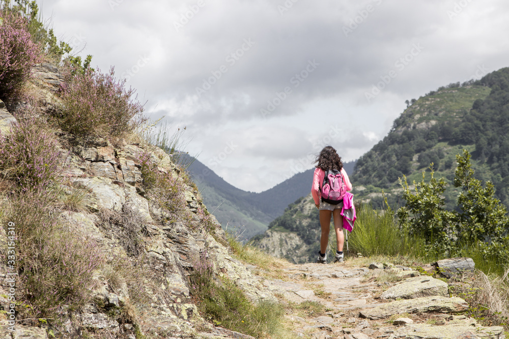 Backside of a girl hiking in the mountains with a backpack 