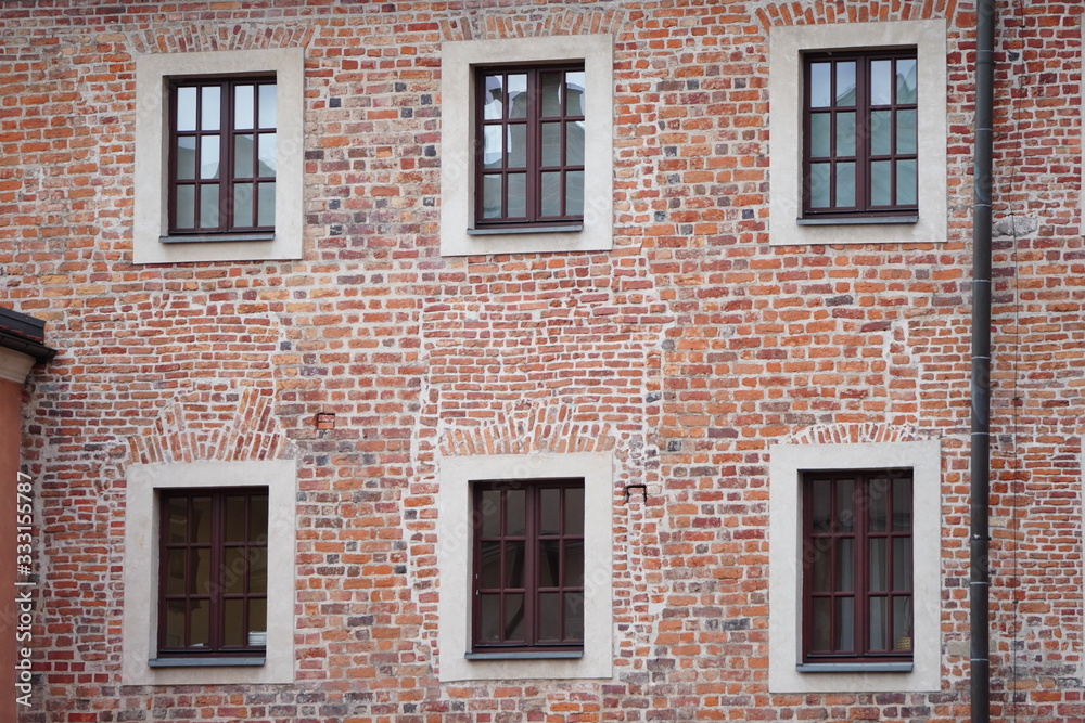 The facade of an old brick building with windows or cornices. Old brick walls