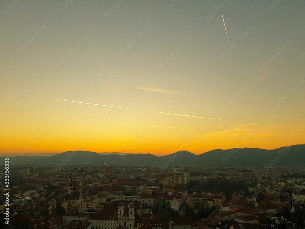 Fototapeta premium Sunset at the Schlossberg in Graz with a view of the west of Graz as well as mountains and trees