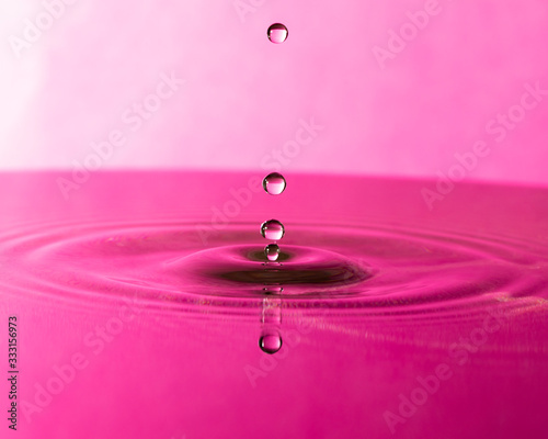 drop of water splashing into water pink color