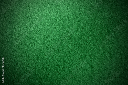 Poker table felt background in dark green color with shade vignette. © Charlie Waradee