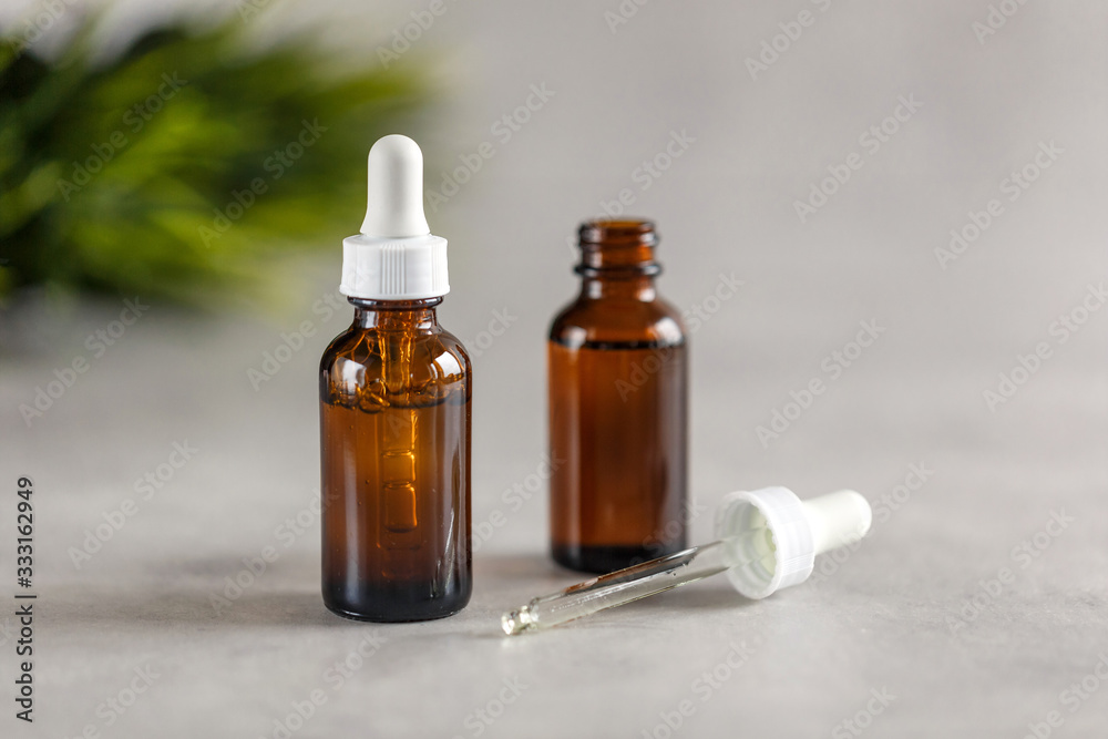 Two brown dropper bottles on a gray background. Beauty concept. Natural oils. Two brown dropper bottles on a gray background. Beauty concept. Natural oils.