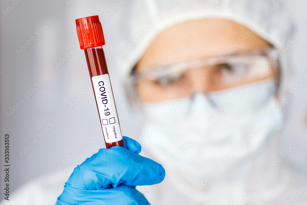 Covid 19 Coronavirus infected blood in tube in hand of scientist female doctor biohazard protection clothing in coronavirus research laboratory. Coronavirus Covid-19 vaccine research Covid 19 Coronavirus infected blood in tube in hand of scientist female doctor biohazard protection clothing in coronavirus research laboratory. Coronavirus Covid-19 vaccine research