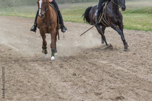 Two racehorses run along the sandy track.