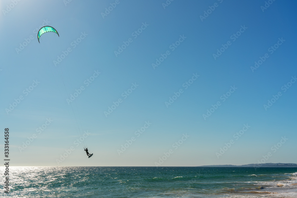 The athlete practices kate board surfing the sea on the waves. Summer in Portugal Algarve.