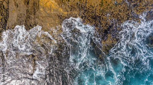 Waves of turquoise water washed by the rocky stone coast of Portugal. Aerial view. © sergojpg
