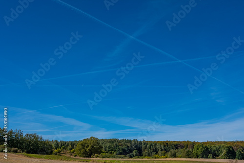 An open sky with chemtrails over fields (a horizontal view)