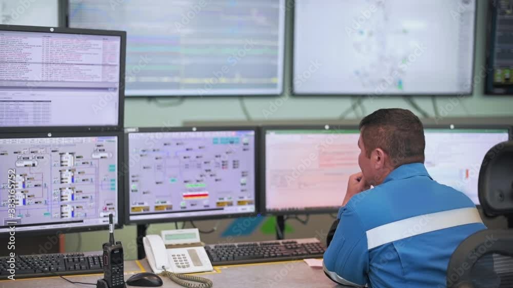 A worker sits in front of many monitors. Production room. Monitoring of technical processes in oil production. Instruments for monitoring indicators in the manufactory. Remote control.